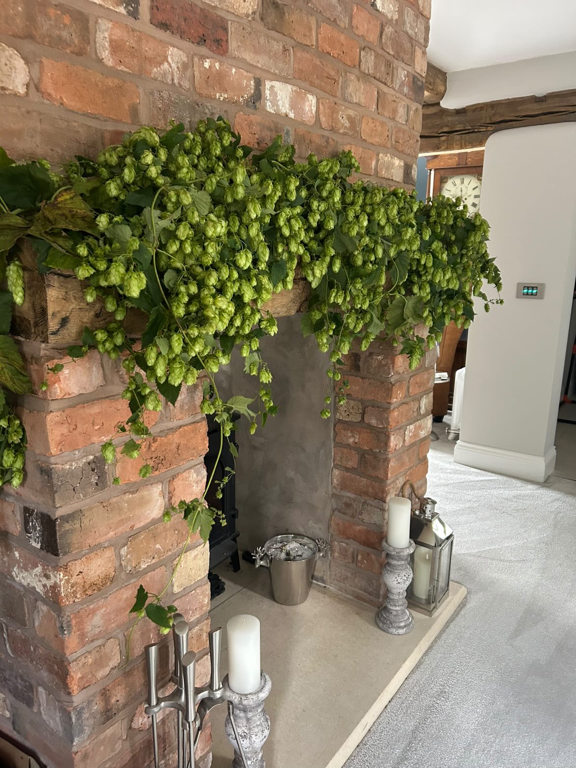 Hop garland cascading over brick fireplace with candles and decorative accessories in modern living room interior